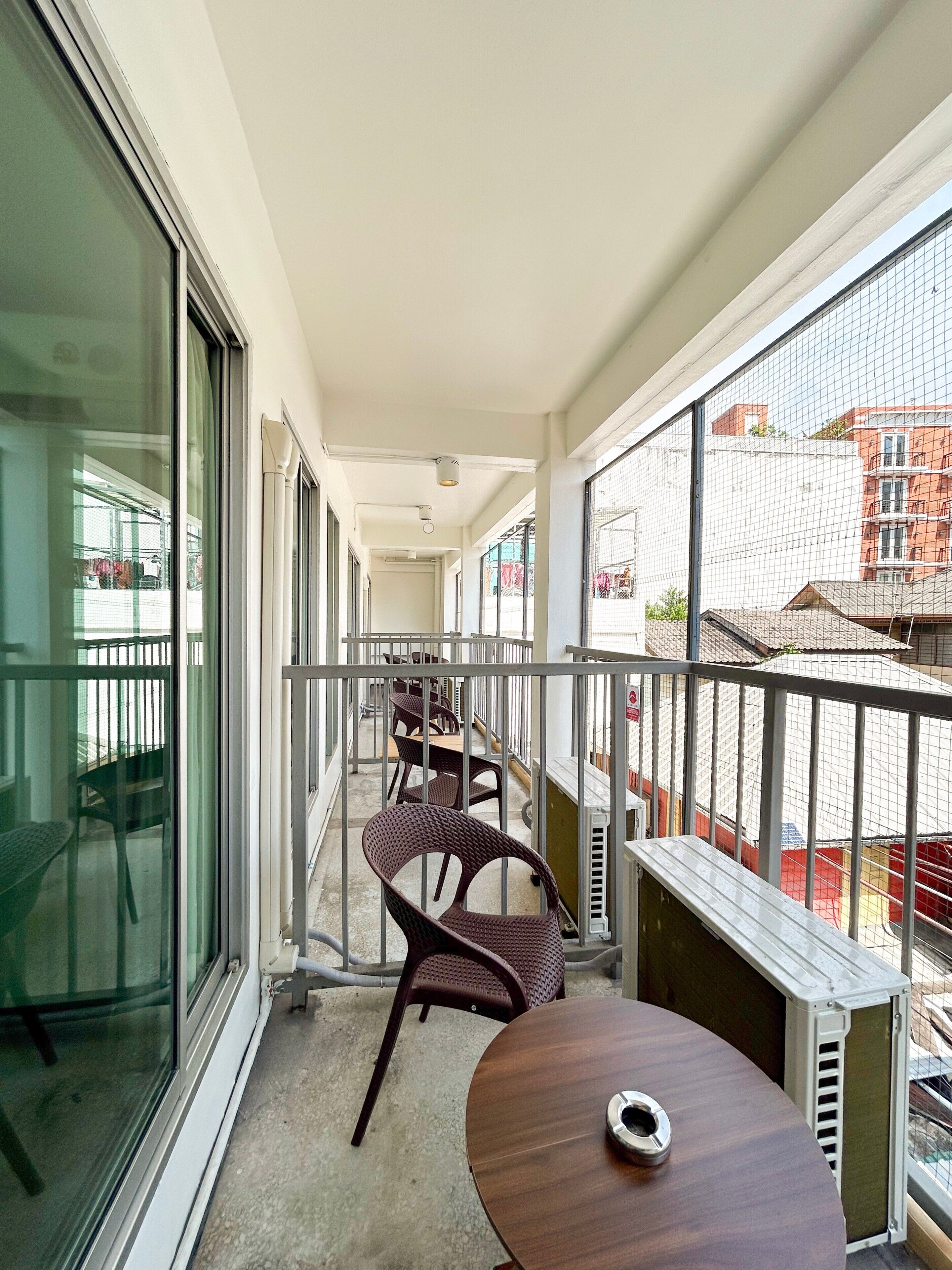 A balcony with a table and chairs, a glass door, and a view of buildings.