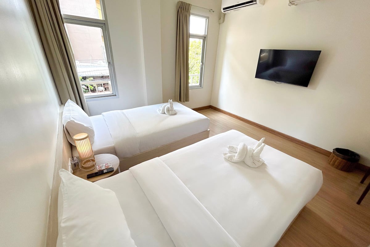 Une chambre d’hôtel avec deux lits, une télévision et une fenêtre avec des rideaux.