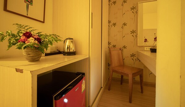 A compact kitchen with a refrigerator, a kettle, and a chair. - Taradii Boutique (Bangkok)