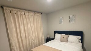A bedroom with a bed, a nightstand, a lamp, and two framed pictures on the wall. - Contemporary 3BR Home Near Base Fast Wi-Fi, Smart TV, Coffee Station (Killeen)