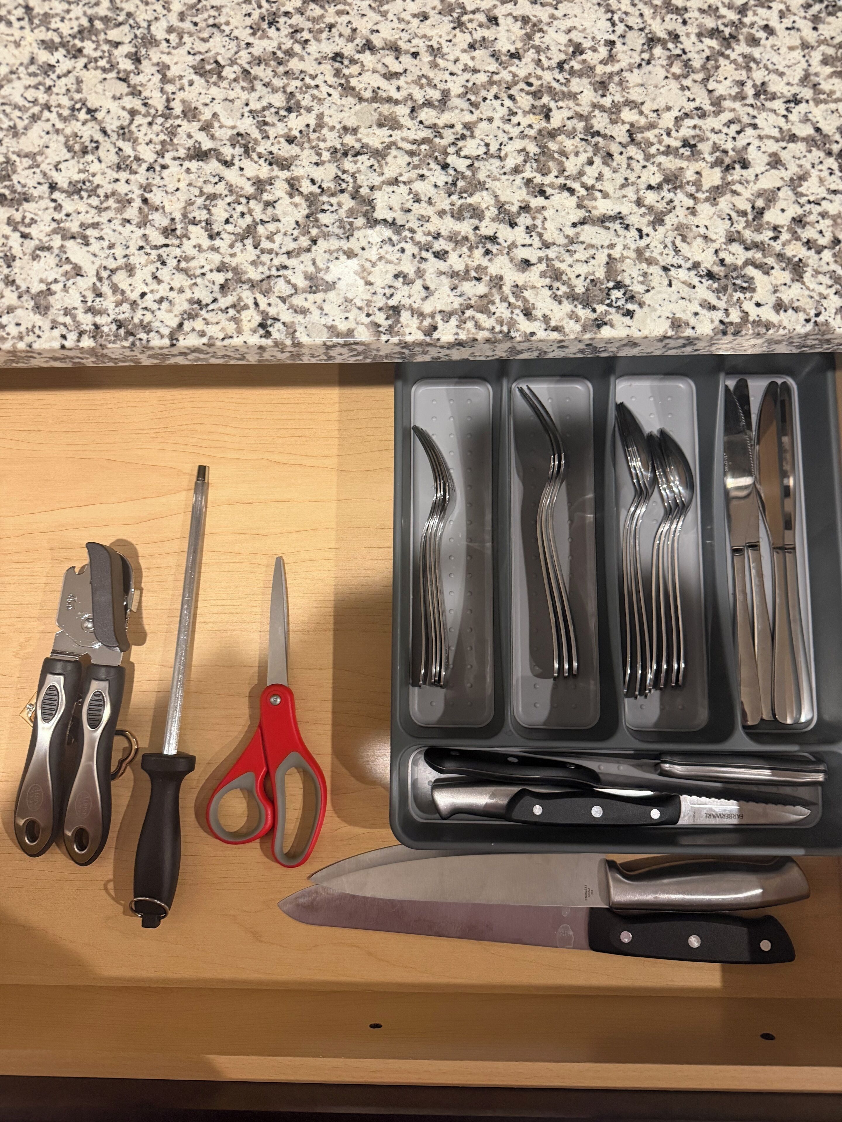 Un plan de travail de cuisine avec divers ustensiles et outils, notamment un couteau, des ciseaux et une pince.