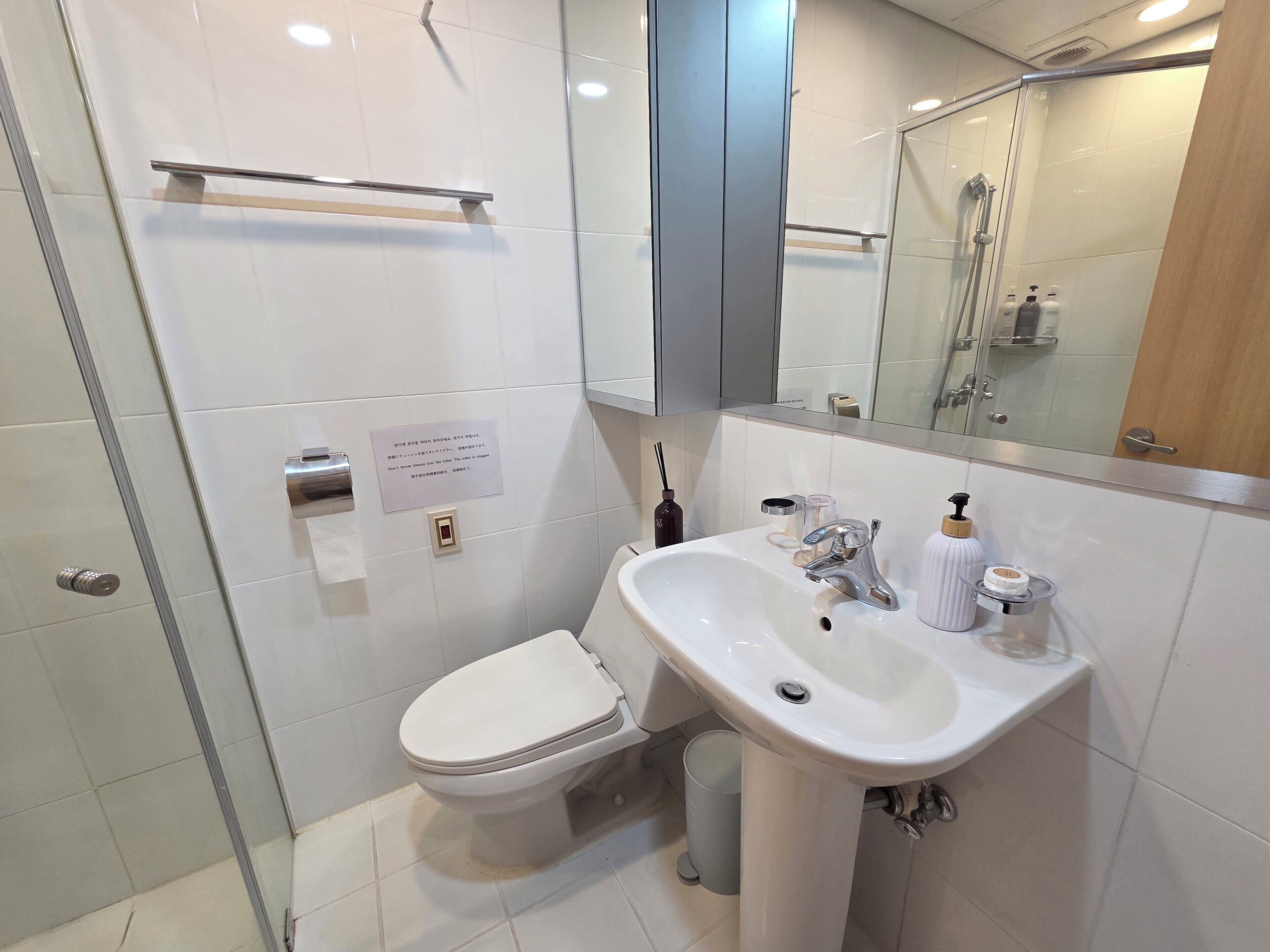 Une salle de bain moderne équipée de toilettes, d’un lavabo et d’une douche à parois de verre.