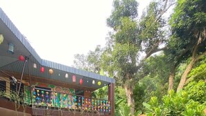 A pool area with a tiled edge, surrounded by orange and red cushions, and a wooden deck. - Chillin' House (Hai Phong)