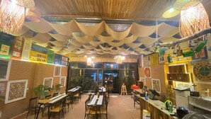 A restaurant with wooden ceiling, hanging paper lanterns, and a brick wall with framed pictures. Tables and chairs are arranged for dining. - Chillin' House (Hai Phong)