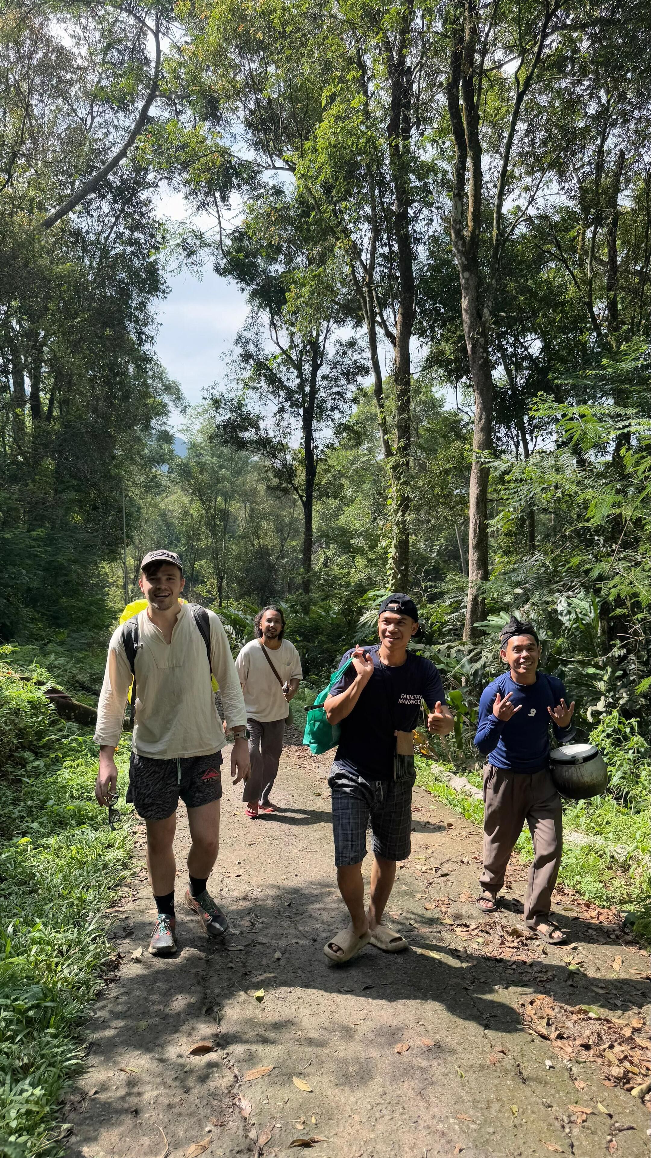 A group of people walking on a dirt path in a forested area.