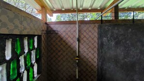 A shower area with a tiled wall, a green glass shower enclosure, and a ceiling with wooden beams. - OZ Cabin by Farmstay Managel (Cianjur)
