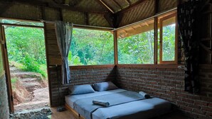 A cozy room with a bed, large windows, and a view of greenery outside. - OZ Cabin by Farmstay Managel (Cianjur)