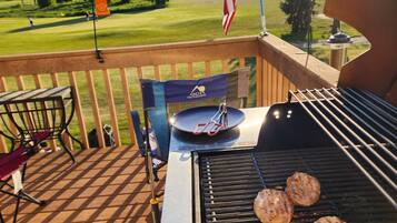 Un barbecue avec de la viande dessus, un drapeau et une vue sur un terrain de golf.