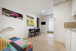 Eine moderne Küche mit weißen Schränken, ein Essbereich mit Tisch und Stühlen sowie ein großes Fenster für natürliches Licht.