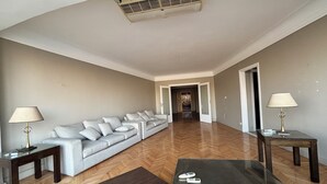 A spacious living room with a grey sofa, two side tables with lamps, a wooden coffee table, and a herringbone floor. - Cosy Nile view Rowers 3 bedroom condo (Giza Governorate)