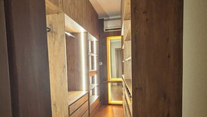 A narrow hallway with wooden walls and a wooden floor. Shelves are built into the walls, and there is a door at the end of the hallway. - Cosy Nile view Rowers 3 bedroom condo (Giza Governorate)