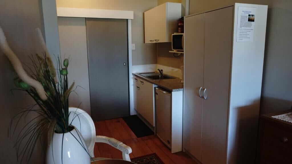 A compact kitchen with white cabinets, a built-in microwave, and a small sink.