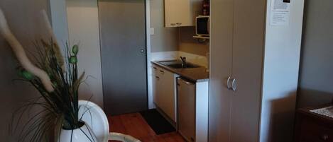 A compact kitchen with white cabinets, a built-in microwave, and a small sink.
