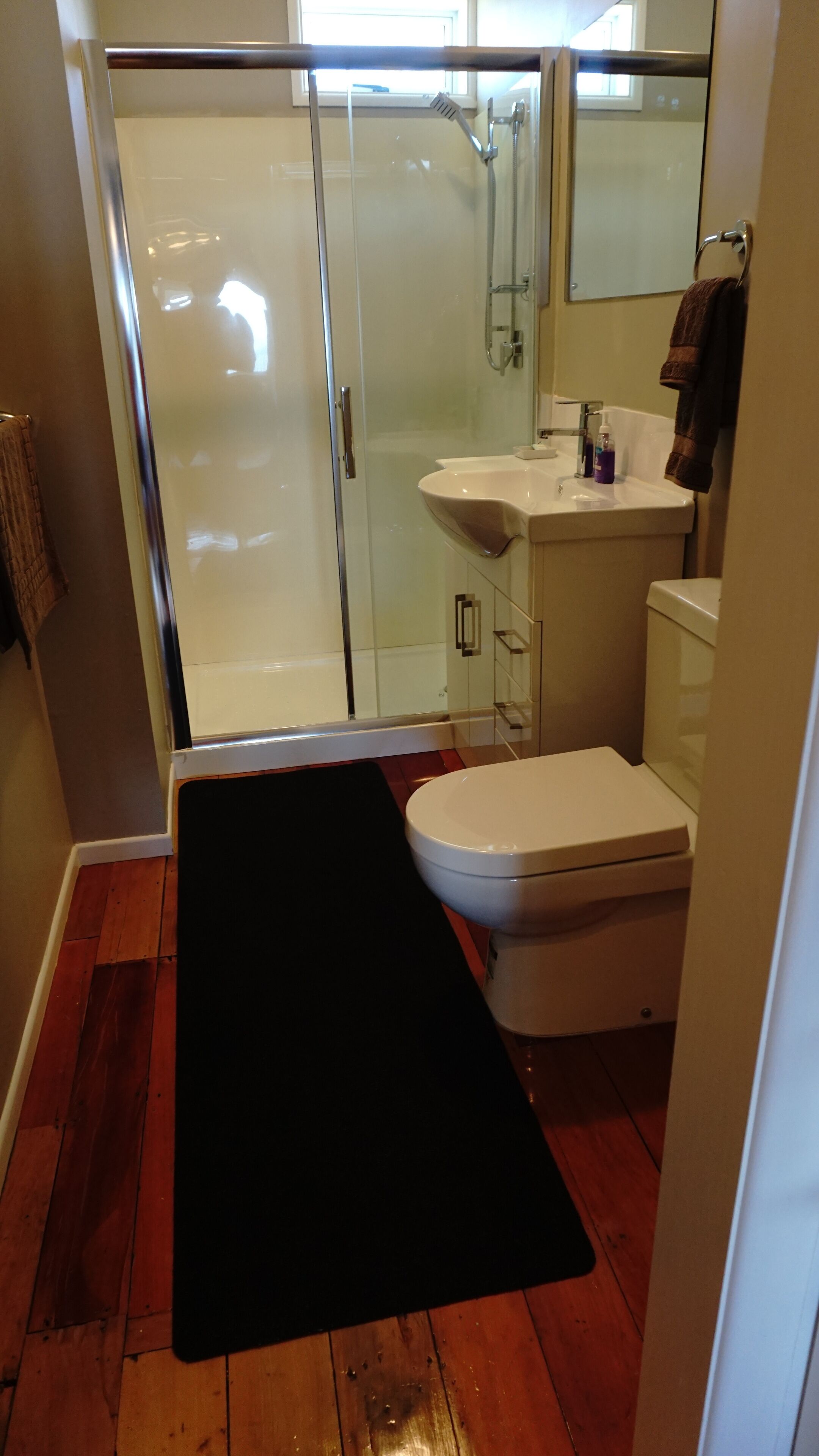 A bathroom with a glass shower enclosure, a white sink, and a toilet.