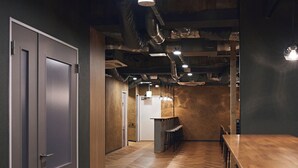 A modern interior with a herringbone wooden floor, a bar area, and a seating section. - Shijo Guesthouse HIVE - Hostel  (Kyoto)
