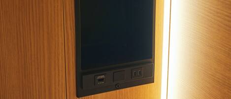 A tablet on a wooden surface with a USB port, a power outlet, and a label indicating 'USB Charge Only'.