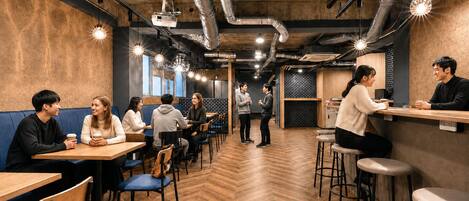 Um café moderno com piso de madeira, dutos de metal e iluminação pendente.