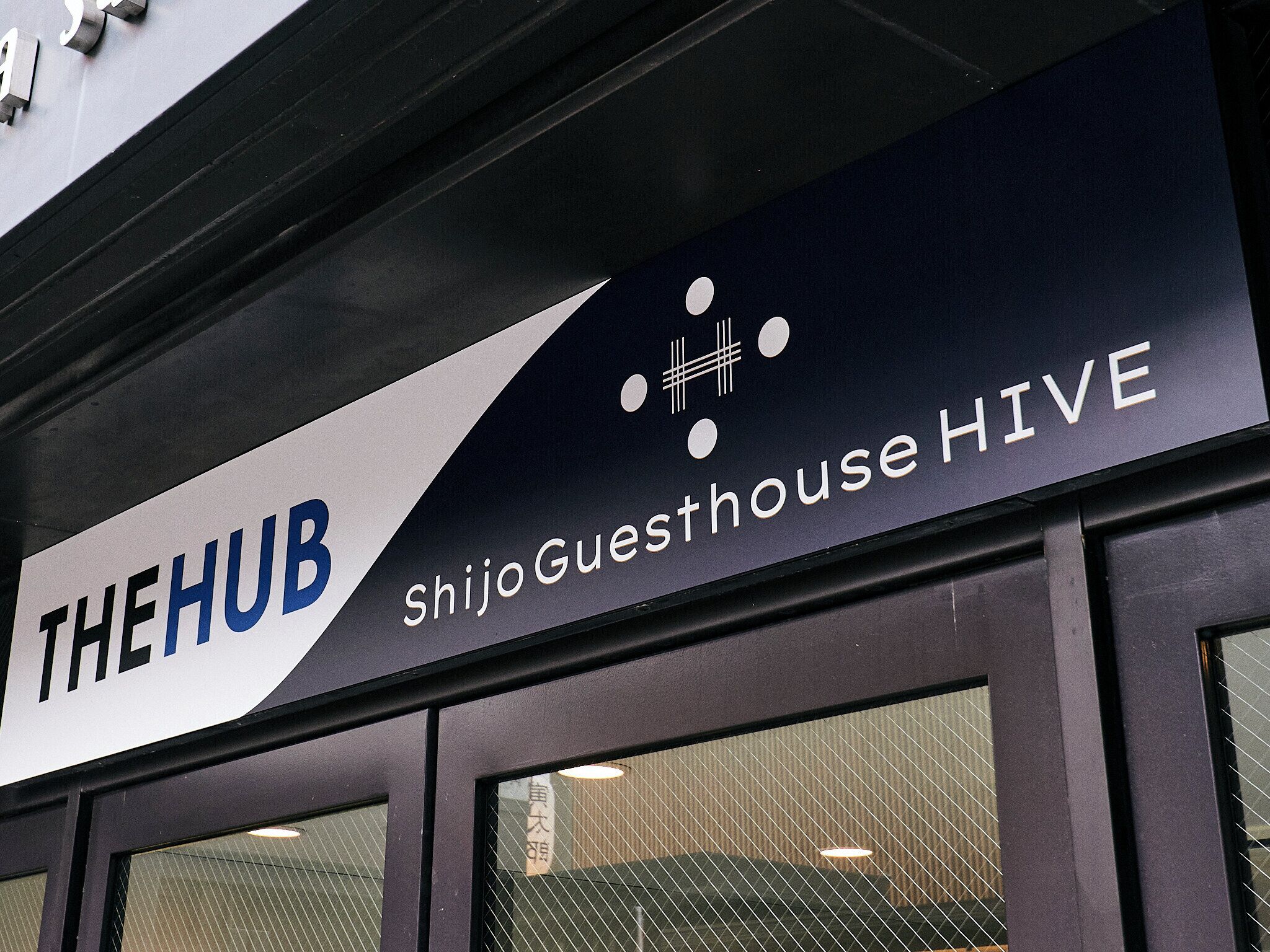 A sign for 'The Hub Shijo Guesthouse HIVE' with a modern design.