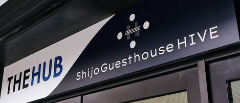 A sign for 'The Hub Shijo Guesthouse HIVE' with a modern design.
