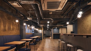 A restaurant interior with wooden tables, blue booths, and bar stools. - Shijo Guesthouse HIVE - Hostel  (Kyoto)