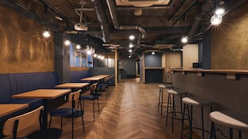 A restaurant interior with wooden tables, blue booths, and bar stools.