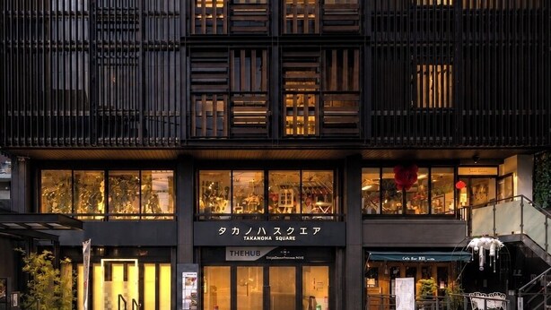A modern building with large windows, a sign reading 'Takanohasquare,' and a visible entrance. - Shijo Guesthouse HIVE - Hostel  (Kyoto)