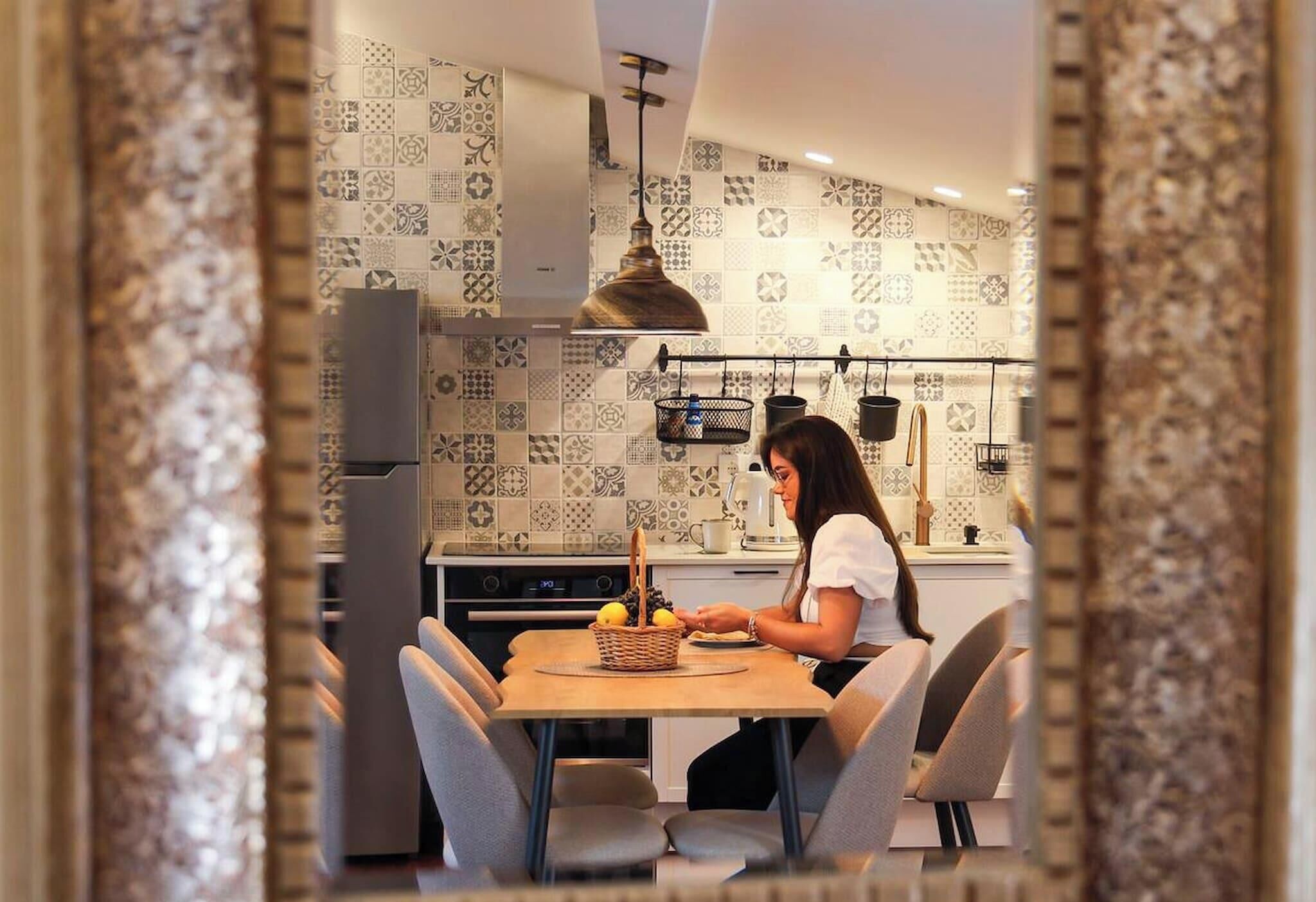 Une cuisine moderne avec des carreaux décoratifs, un luminaire suspendu et un coin repas avec des chaises.