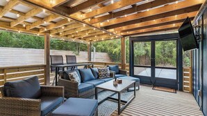 An outdoor deck with a wooden ceiling, wicker furniture, and a television. - The Big Salty -Mid South SSI (St. Simons Island)