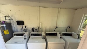 A laundry room with four washing machines, a control panel, and a water heater. - Myakka Cove Glamping (Venice)
