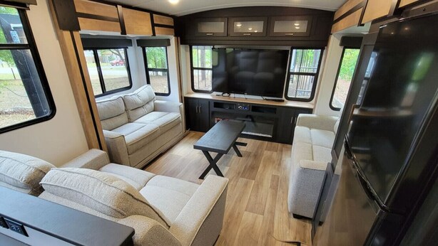 Ein modernes Wohnmobil-Interieur mit einer Sitzecke, Esstisch, Küchenzeile und Fernseher.