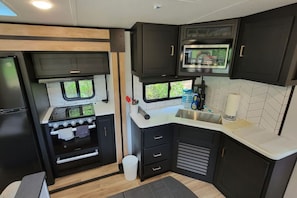 Cocina compacta para autocaravana, con estufa, horno, microondas y fregadero.