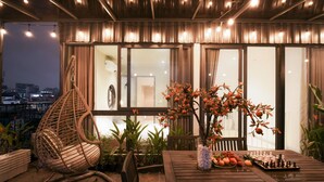 Un espacio al aire libre acogedor con una mesa de madera, una silla colgante y un tablero de ajedrez.