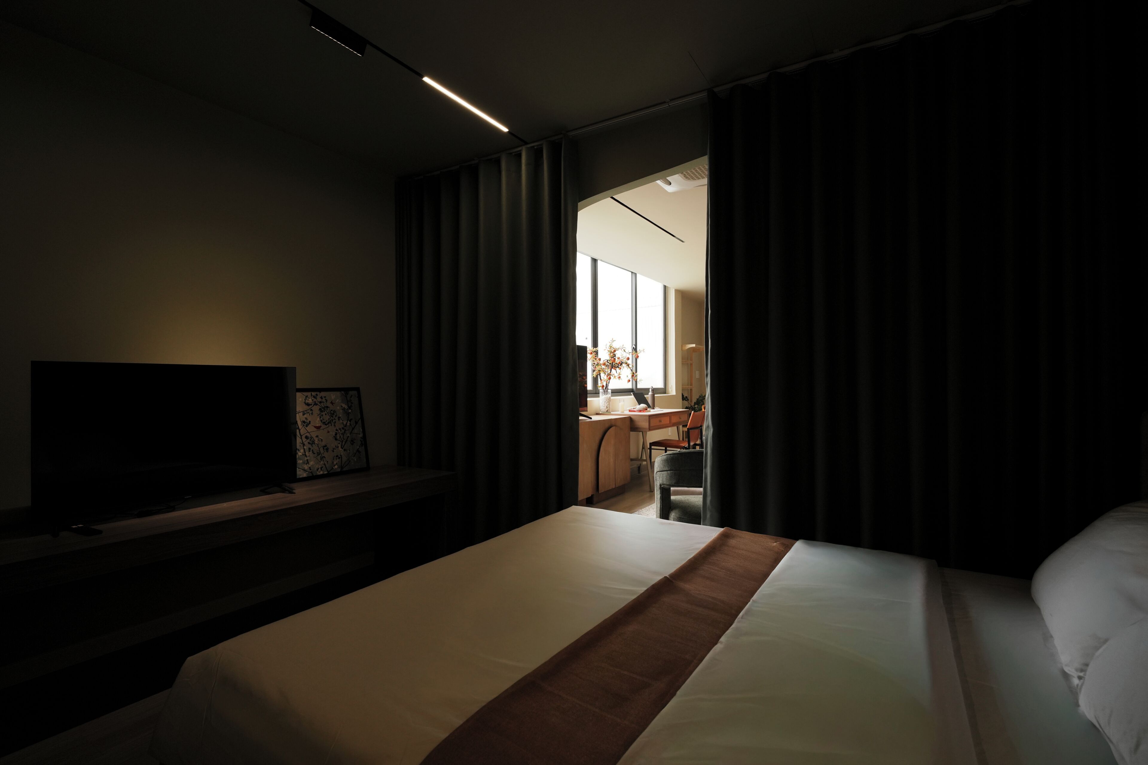 A hotel room with a bed, a TV, a desk, and a chair.
