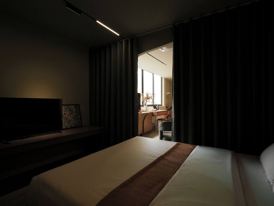 A hotel room with a bed, a TV, a desk, and a chair.
