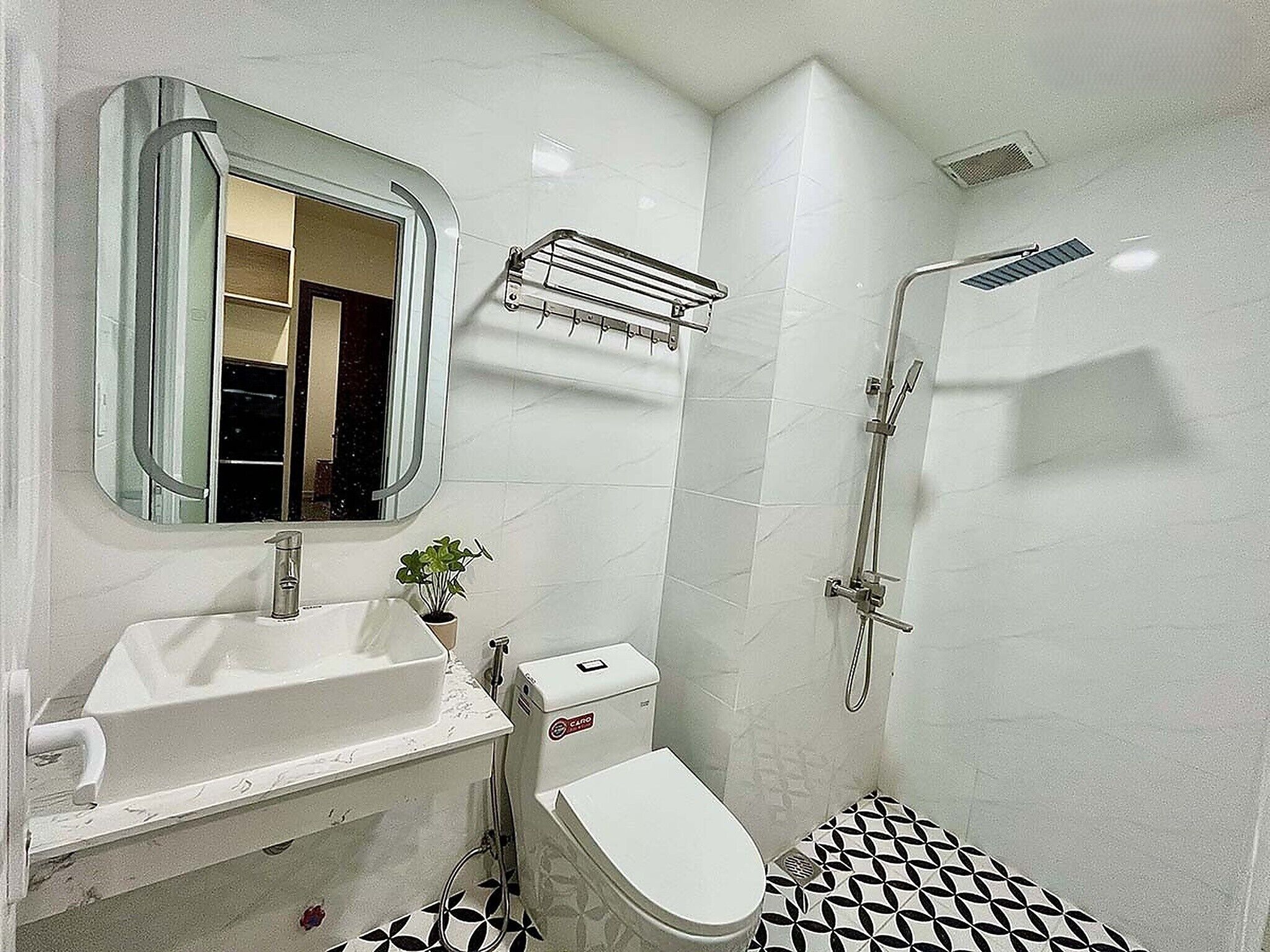 Un baño con lavamanos blanco, inodoro, espejo y ducha.