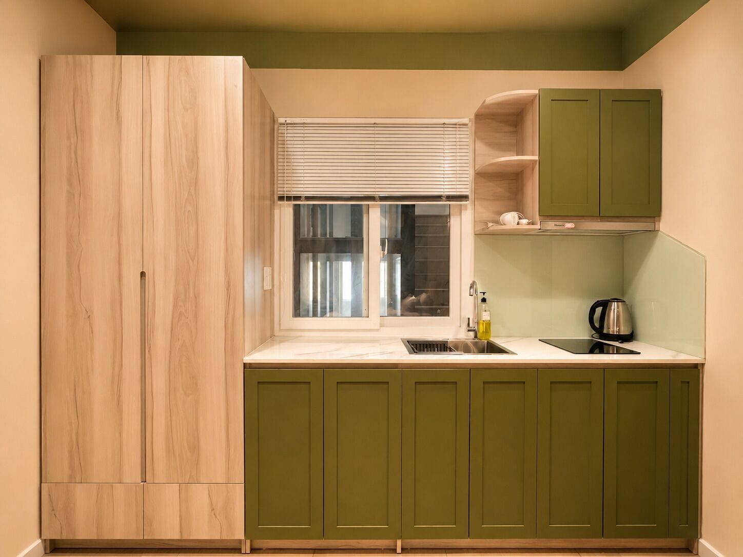 A kitchen with a window, a sink, a kettle, and green cabinets.