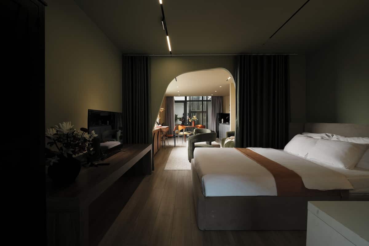 A modern hotel room with a large bed, a desk, and a seating area.