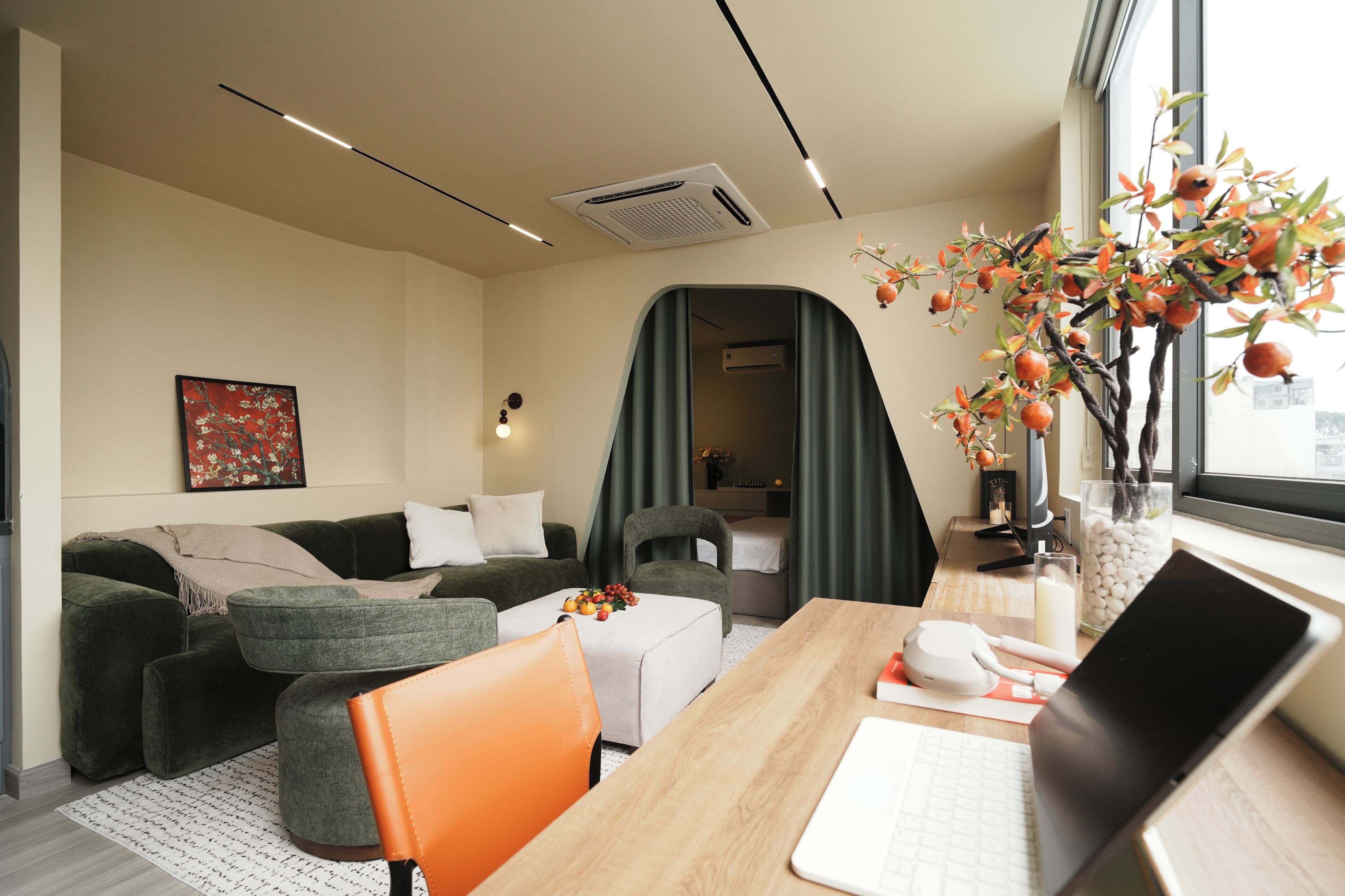 A modern living room with a sofa, a dining table, a laptop, and a decorative plant.