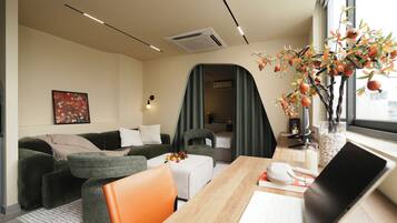 A modern living room with a sofa, a dining table, a laptop, and a decorative plant.
