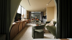 Una sala de estar moderna con un sofá, un comedor y una cocina visibles a través de un arco.