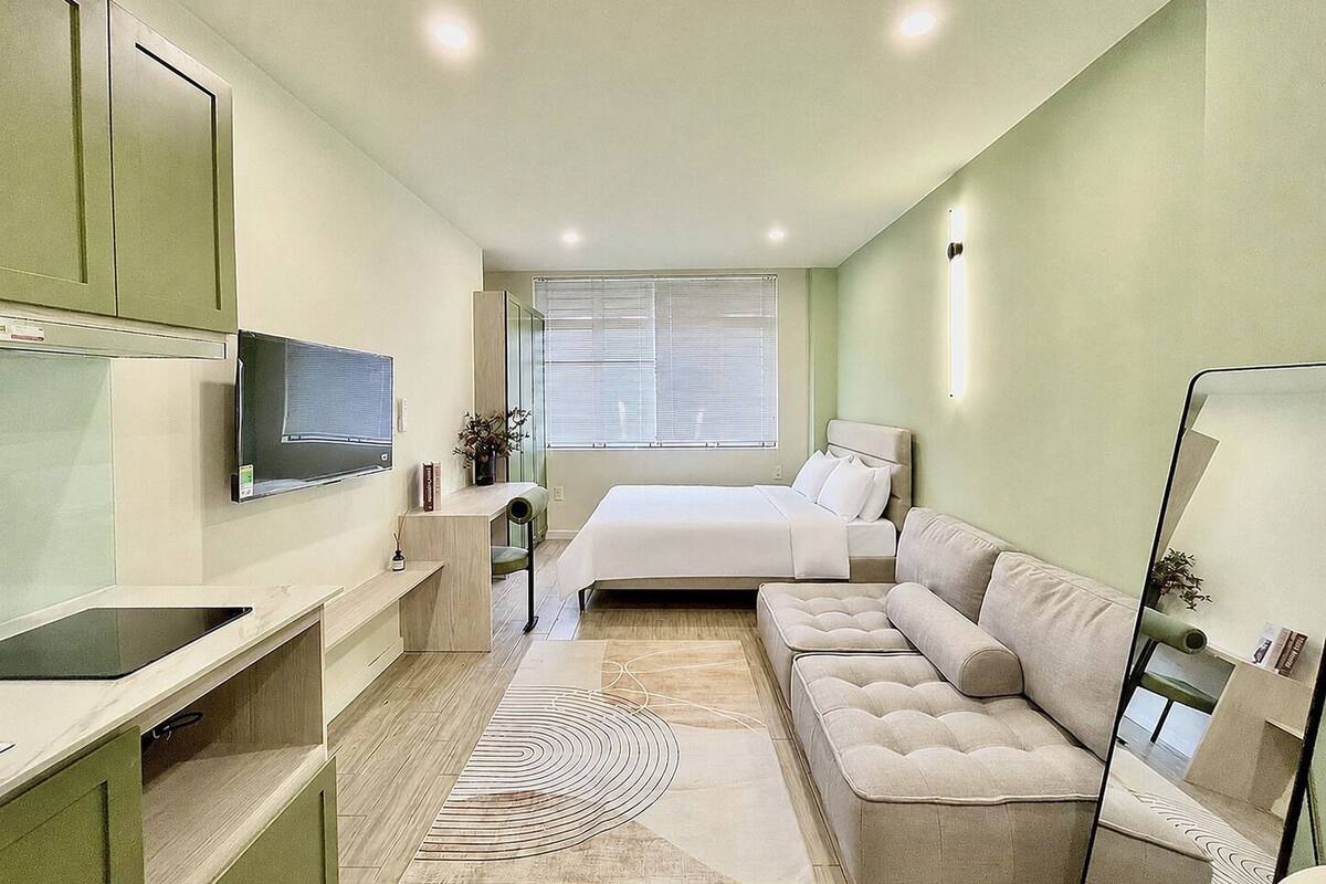 A modern bedroom with a bed, a sofa, a TV, and a desk.