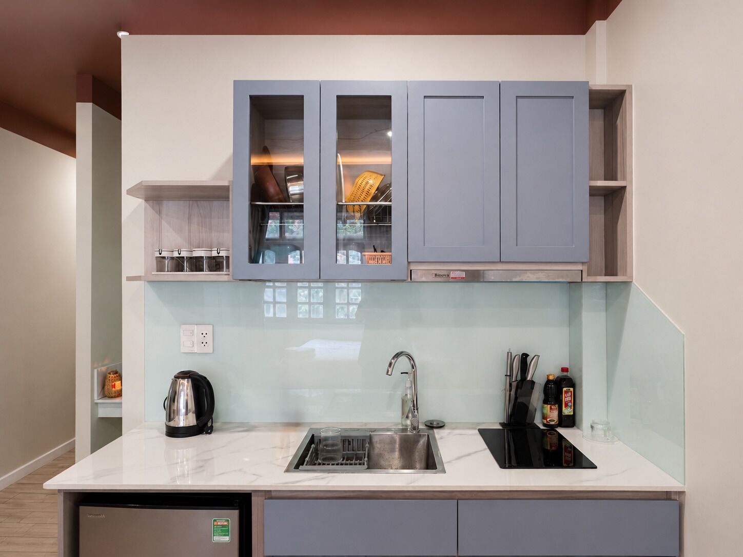 A modern kitchen with a built-in dishwasher, a sink, and cabinets with glass doors.