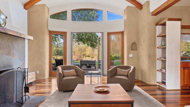 A spacious living room with a fireplace, two armchairs, a coffee table, and a view of the outdoors. - Elegant Cobb House w/ Spa | Pond | Chef Kitchen (Kenwood)