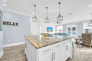 A modern kitchen with a marble countertop, white cabinets, and pendant lights. - Shore Thing Getaway | 1 PM Check in! | Large Private Pool & Pergola! | One Block to the New Tarpon Beach Park! | Crystal Beach Gem, Sleeps 22 (Destin)