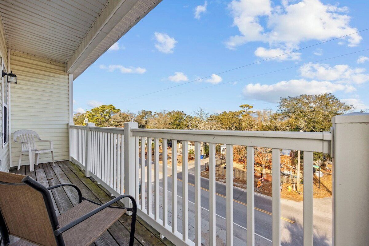A porch with a white railing, a bench, and a chair.