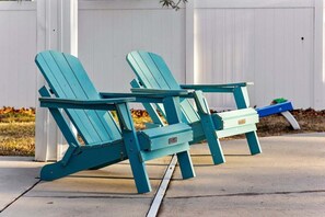 Zwei Adirondack-Stühle mit einem kleinen Tisch davor, auf einer Betonfläche platziert.