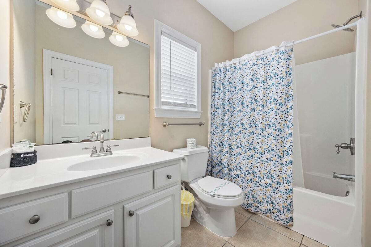 A bathroom with a white sink, toilet, and shower curtain.