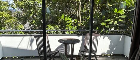 A balcony with a table and chairs, surrounded by lush greenery and trees.