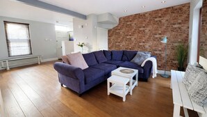 A modern living room with a sectional sofa, a coffee table, and a brick accent wall. - Contemporary 2BDR City Retreat (Dublin)