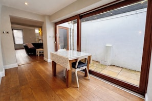 A room with a wooden floor, a table with a white tablecloth, a chair, and a sliding glass door leading to an outdoor area. - Contemporary 2BDR City Retreat (Dublin)